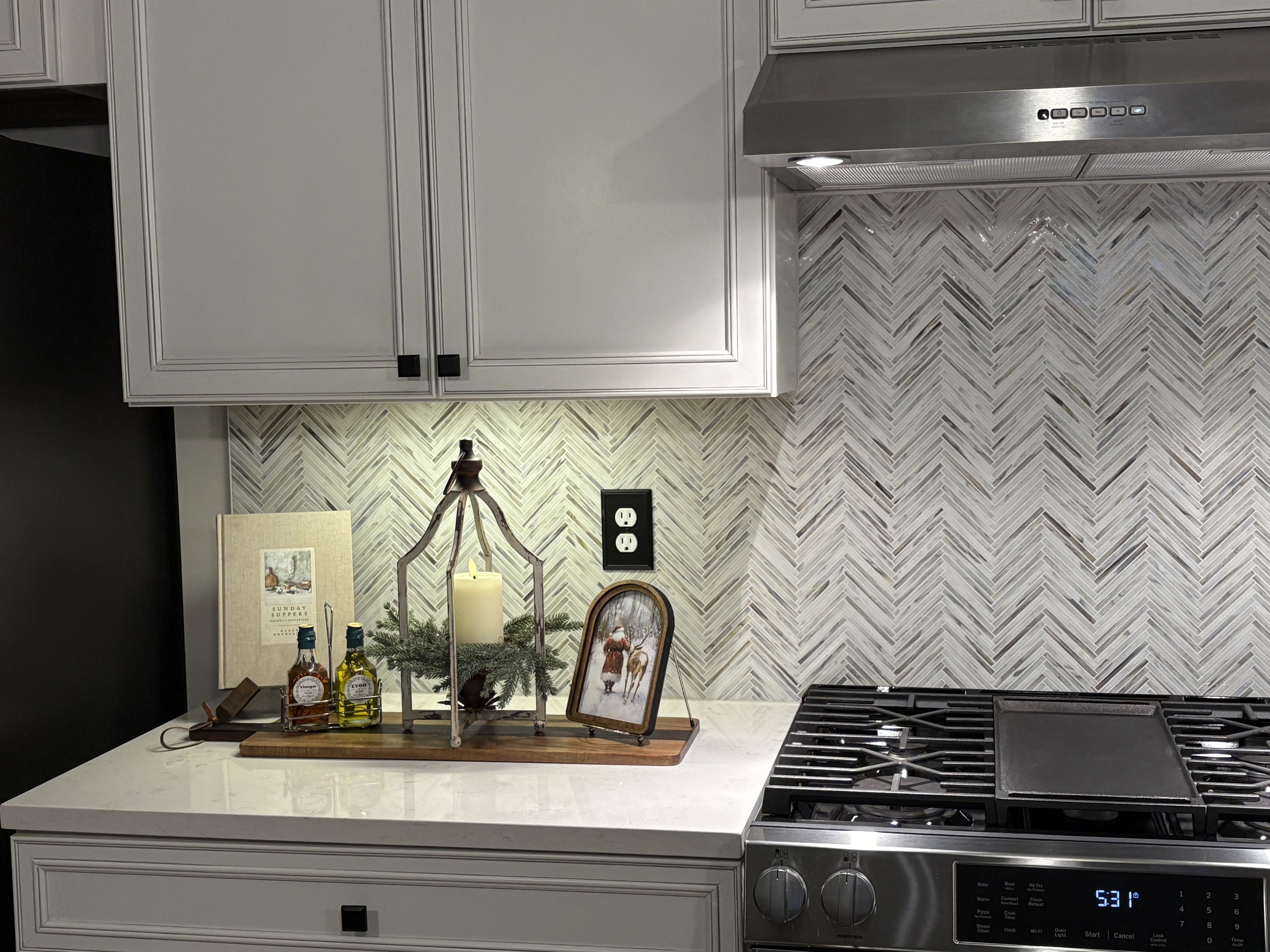 The left view of a kitchen with a white tile backsplash next to the stove